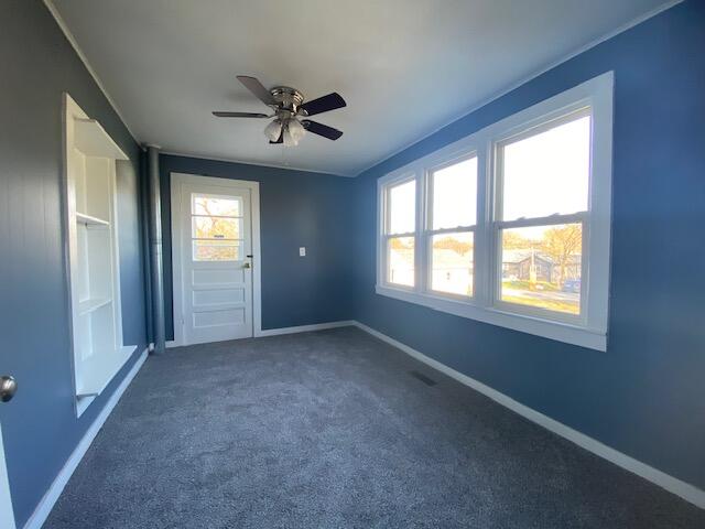 spare room featuring ceiling fan and dark colored carpet