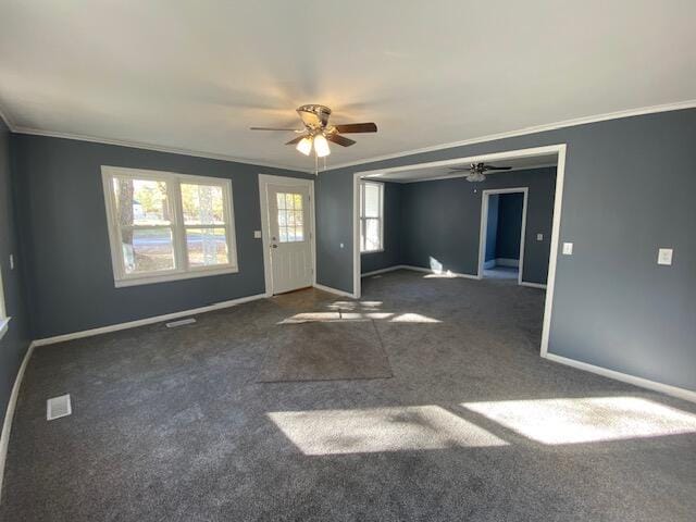 unfurnished living room featuring ceiling fan, dark carpet, and ornamental molding