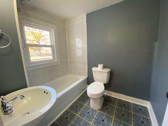 full bathroom featuring bathtub / shower combination, sink, tile patterned flooring, toilet, and tile walls