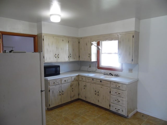 kitchen with sink, light brown cabinets, and white refrigerator