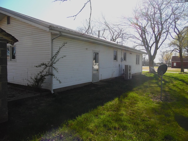 view of side of home featuring ac unit and a yard