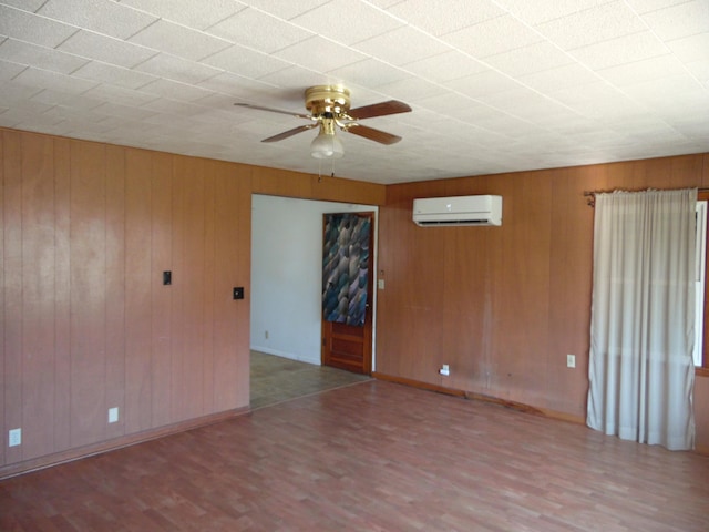 spare room featuring hardwood / wood-style floors, ceiling fan, a wall mounted air conditioner, and wooden walls