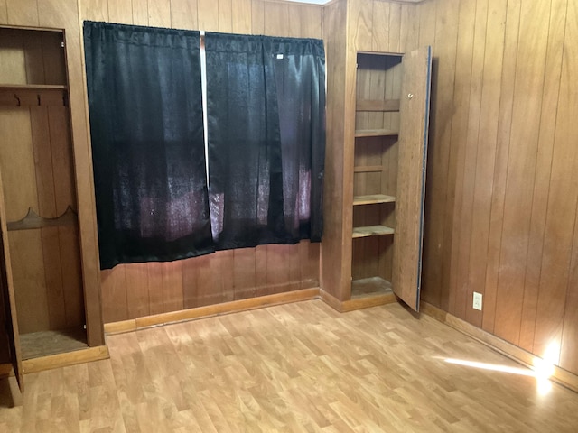 interior space with light hardwood / wood-style floors and wooden walls