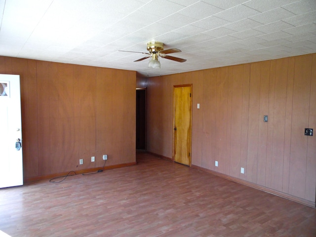 spare room with light hardwood / wood-style flooring, ceiling fan, and wood walls