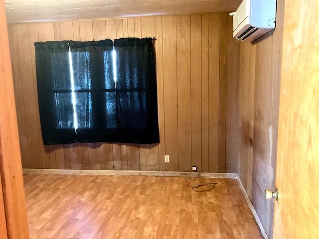 unfurnished room featuring hardwood / wood-style floors, wood walls, and a wall mounted air conditioner