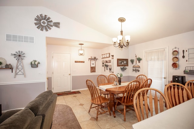 tiled dining area featuring a notable chandelier and lofted ceiling