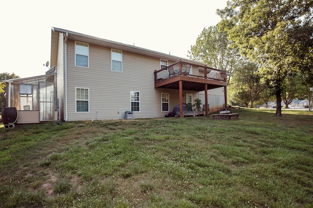 rear view of property featuring a yard, a wooden deck, and a sunroom