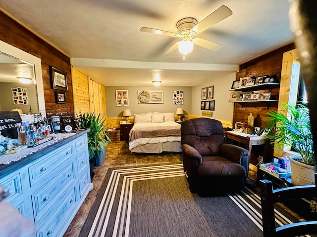 bedroom with ceiling fan and wood walls