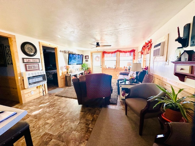 living room featuring a textured ceiling, heating unit, ceiling fan, wooden walls, and an AC wall unit