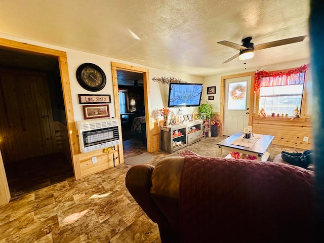 living room with heating unit, ceiling fan, and a textured ceiling