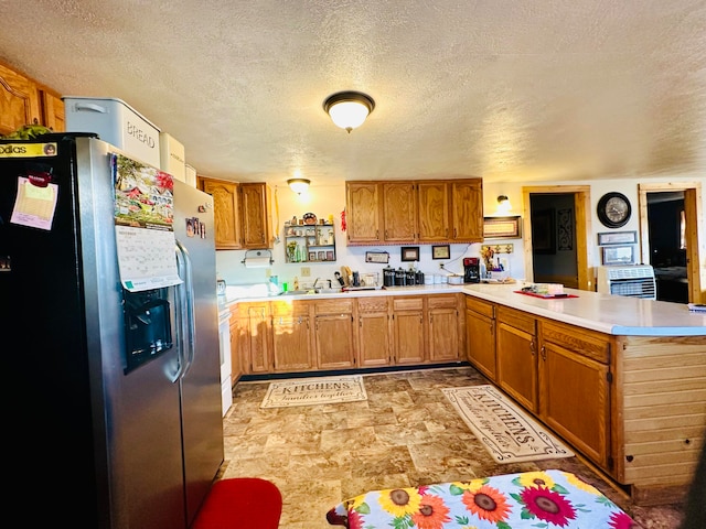 kitchen with kitchen peninsula, stainless steel fridge, sink, and a textured ceiling