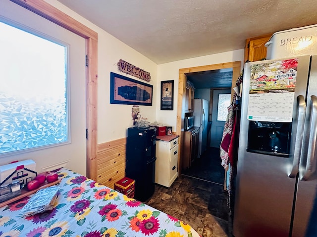 bedroom with stainless steel fridge, stainless steel fridge with ice dispenser, and a textured ceiling