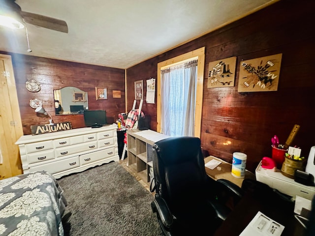 carpeted office space with ceiling fan and wooden walls