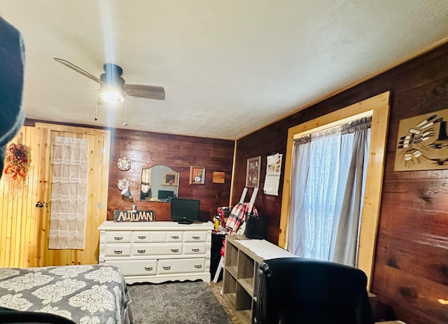 bedroom featuring ceiling fan and wooden walls