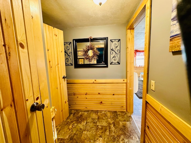 hallway featuring a textured ceiling and wood walls