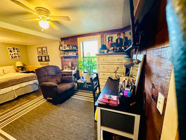 bedroom with ceiling fan, a textured ceiling, and dark colored carpet