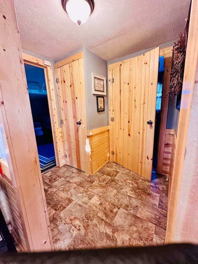 corridor featuring wood walls and a textured ceiling