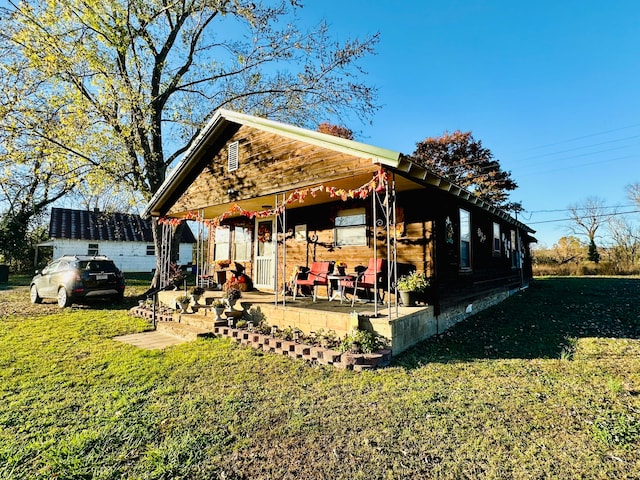 back of property with covered porch and a yard