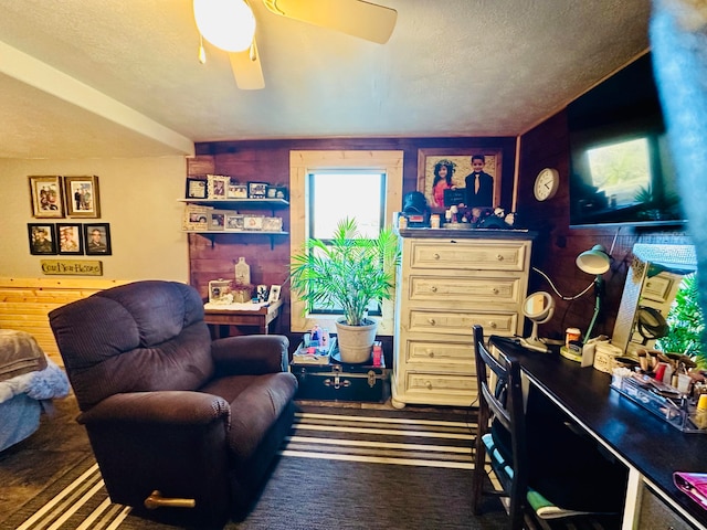 office with ceiling fan, a textured ceiling, and wooden walls