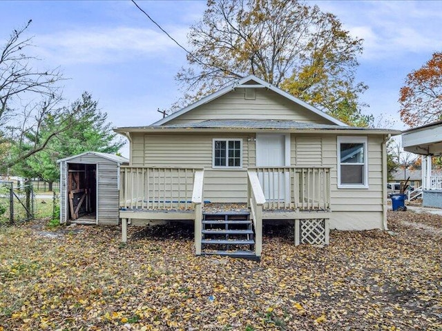 rear view of property featuring a wooden deck and a storage unit