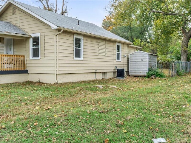 view of home's exterior featuring a lawn, central AC unit, and a storage shed