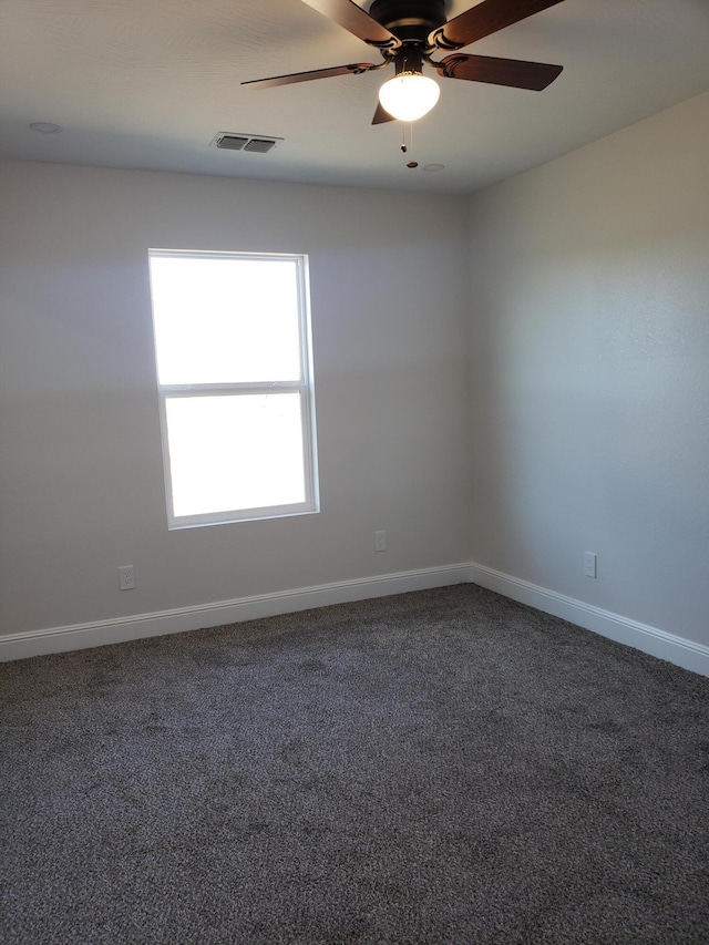 unfurnished room with ceiling fan and dark carpet