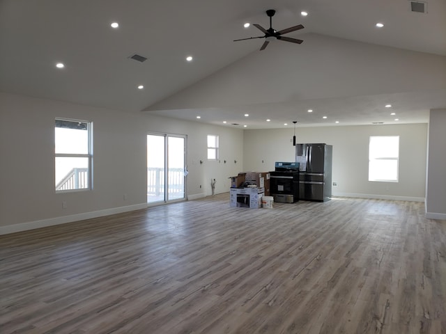 unfurnished living room featuring light wood-type flooring, high vaulted ceiling, a wealth of natural light, and ceiling fan