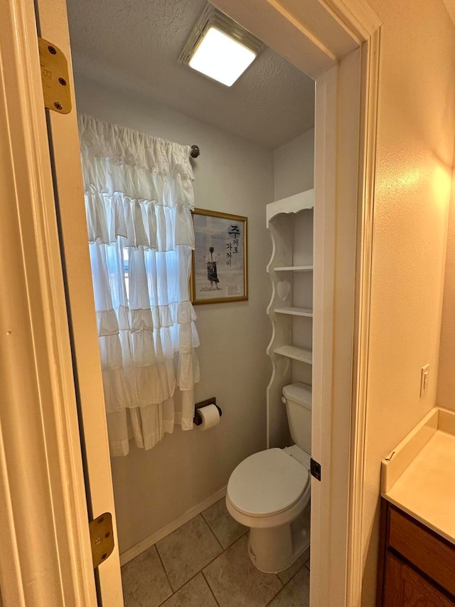 bathroom with tile patterned floors, vanity, toilet, and a textured ceiling