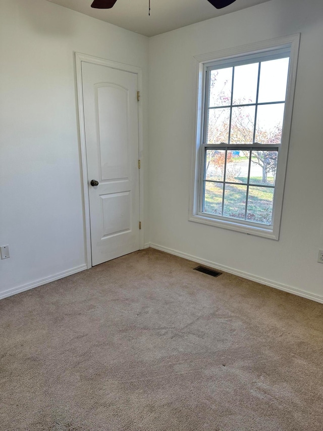 carpeted spare room with ceiling fan