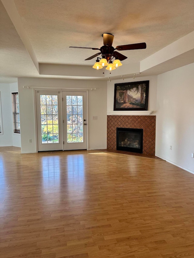 unfurnished living room with hardwood / wood-style flooring, ceiling fan, a fireplace, and a textured ceiling