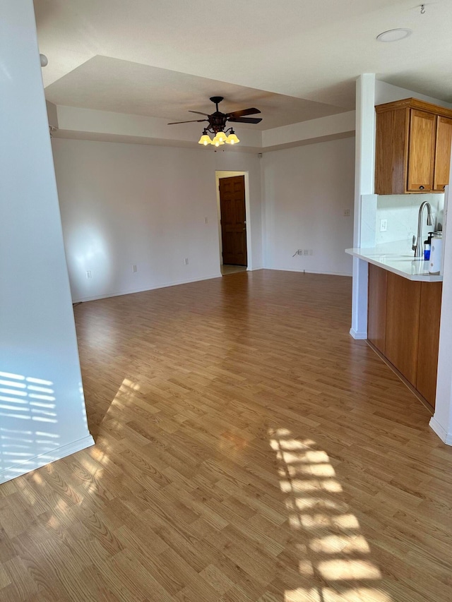 unfurnished living room with hardwood / wood-style floors, ceiling fan, lofted ceiling, and sink