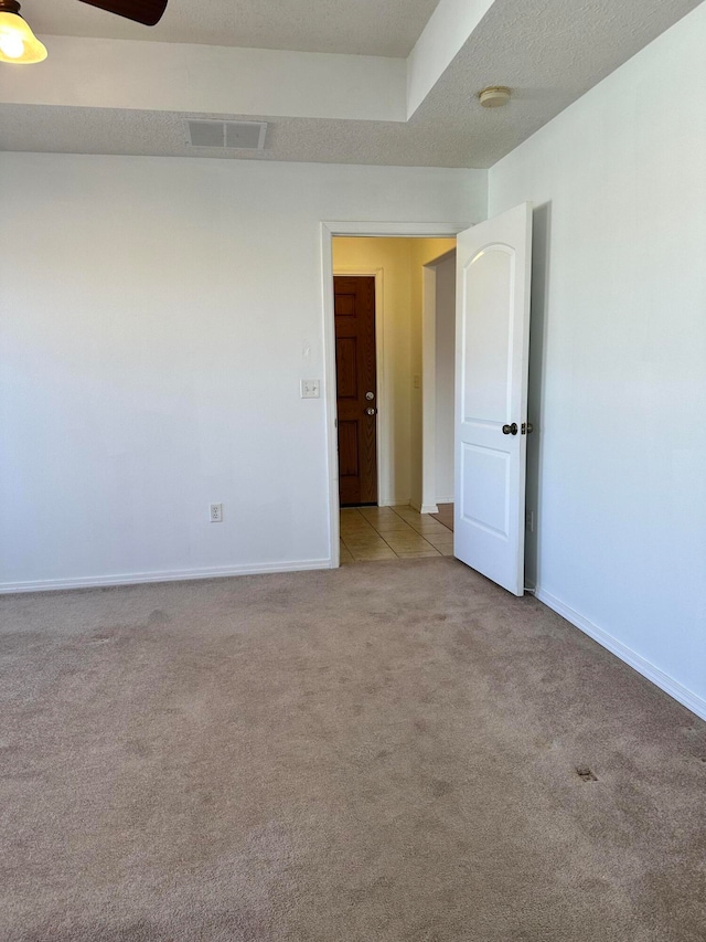 spare room with light colored carpet and a textured ceiling