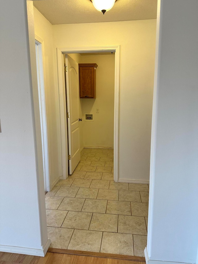 hallway featuring light tile patterned floors and a textured ceiling