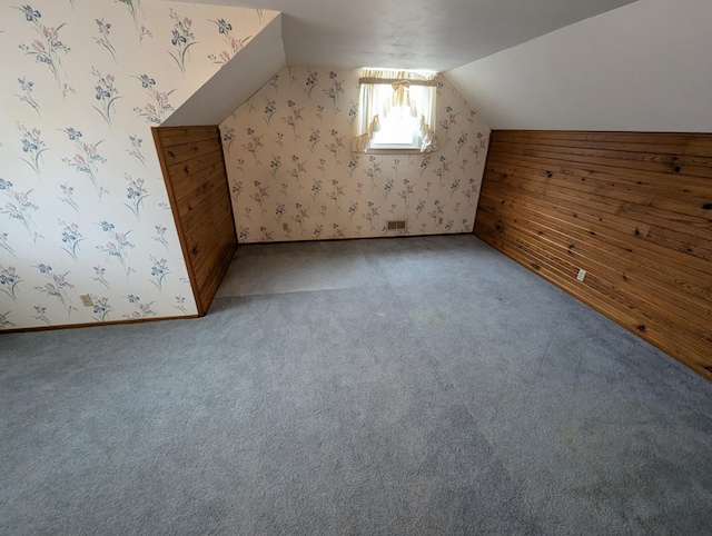 bonus room with wooden walls, carpet floors, and vaulted ceiling