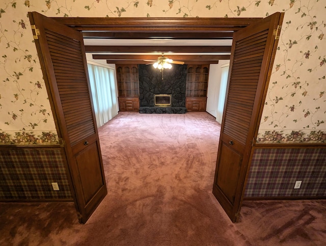 unfurnished living room featuring carpet, beam ceiling, and a high end fireplace