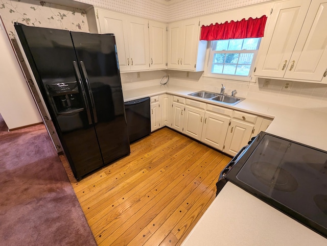 kitchen featuring white cabinetry, sink, black appliances, and light wood-type flooring