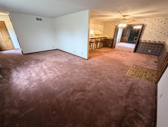 empty room with a textured ceiling, carpet floors, and ceiling fan