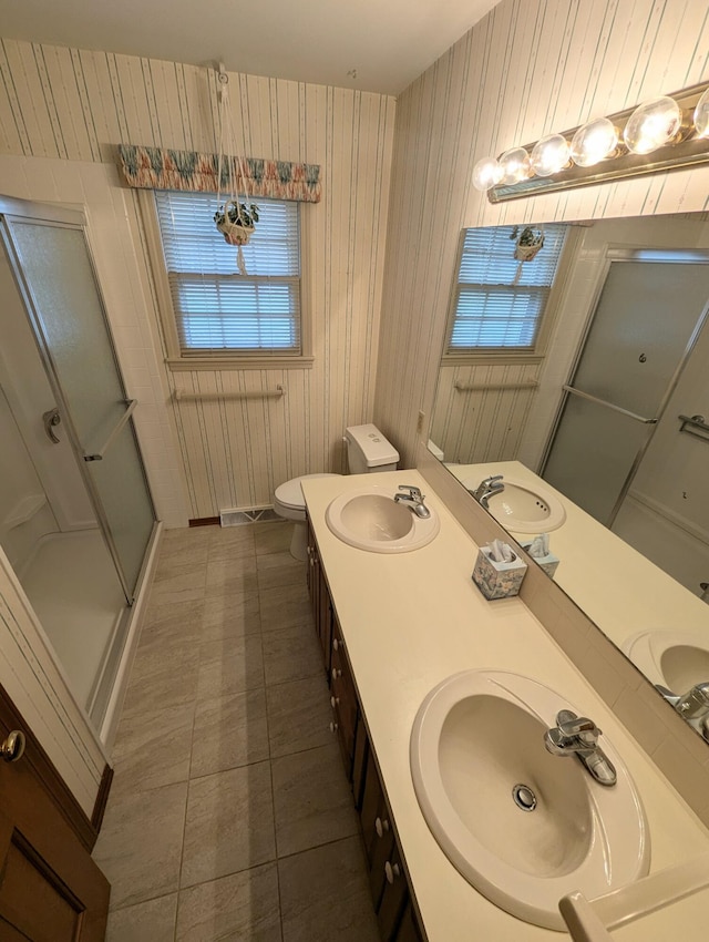 bathroom featuring vanity, tile patterned flooring, toilet, a wealth of natural light, and a shower with shower door