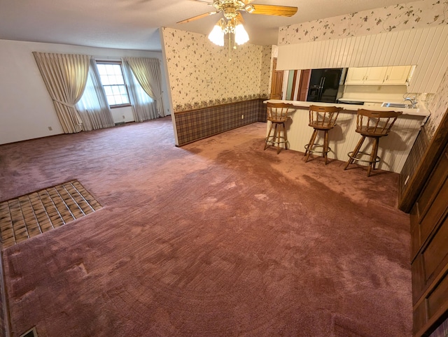 unfurnished living room featuring ceiling fan and dark carpet