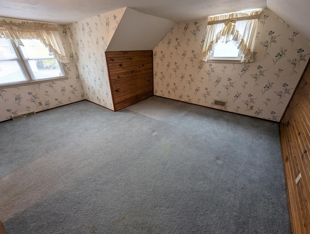 additional living space with carpet flooring, wood walls, and lofted ceiling