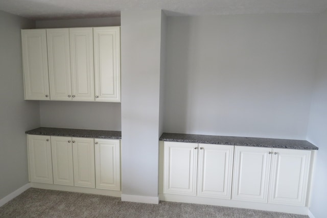 interior space featuring white cabinets and light carpet