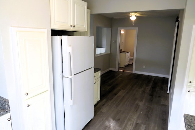 kitchen with dark hardwood / wood-style flooring, ceiling fan, dark stone countertops, white cabinets, and white fridge