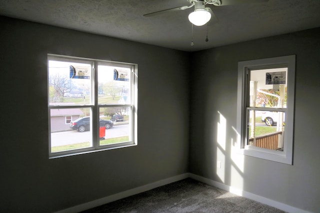 unfurnished room featuring carpet, a textured ceiling, a wealth of natural light, and ceiling fan