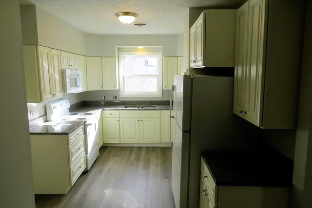 kitchen with white appliances, sink, a textured ceiling, light hardwood / wood-style floors, and white cabinetry