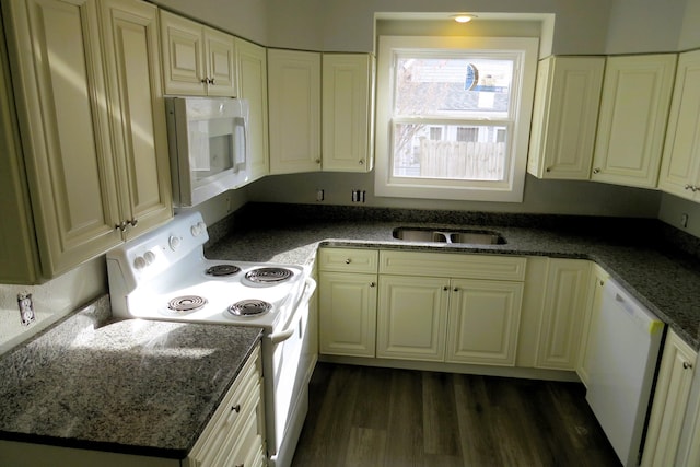 kitchen featuring dark stone countertops, sink, white appliances, and dark wood-type flooring