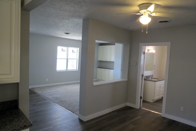 hall with a textured ceiling, dark hardwood / wood-style floors, and sink