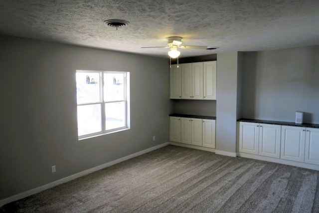 spare room featuring carpet flooring, ceiling fan, and a textured ceiling