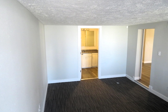 spare room with a textured ceiling and dark wood-type flooring