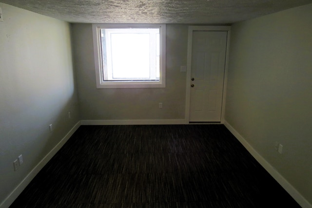 unfurnished room featuring dark hardwood / wood-style flooring and a textured ceiling