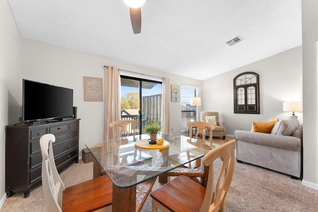 dining room with a textured ceiling, ceiling fan, light carpet, and vaulted ceiling